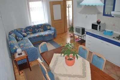 Modri apartma: kotna sedežna garnitura, jedilna miza z modrimi stoli in kuhinjski blok