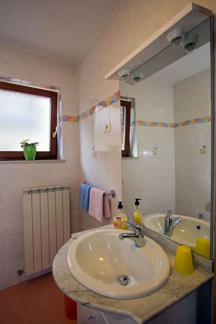 Oranžni apartma: umivalnik z ogledalom in okno v kopalnici