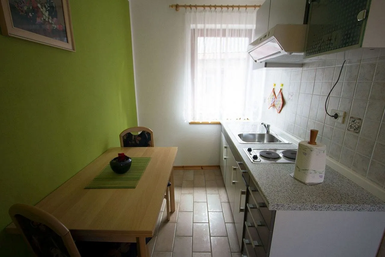 Zeleni apartma: kuhinjska niša in jedilna miza ob zeleni steni